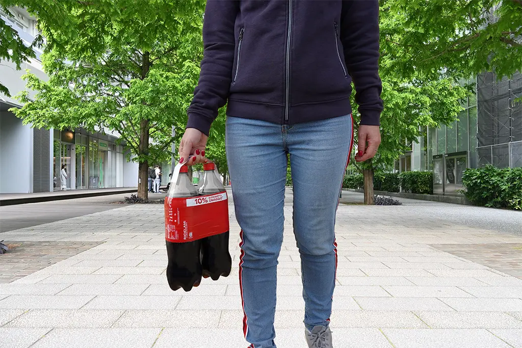 Image of a person carrying a bipack of bottles with adhesive handle and stretch sleeve label.