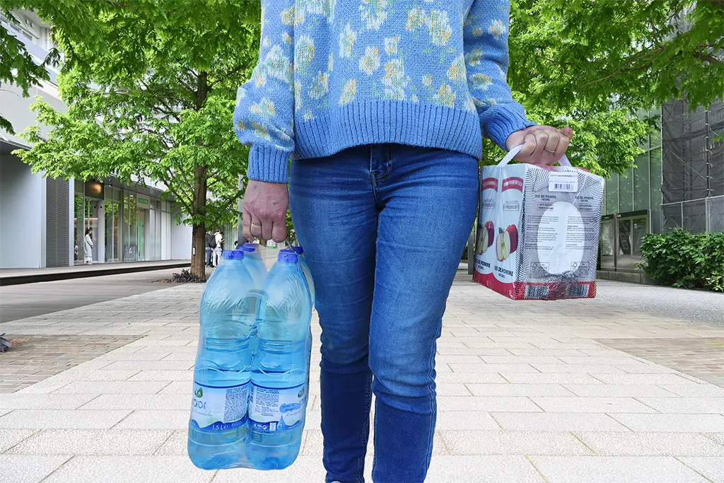 Image of a person carrying beverage packages with a sticky handle.